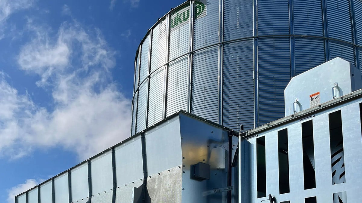 A large grain silo set against a blue sky, likely situated on a modern farm.